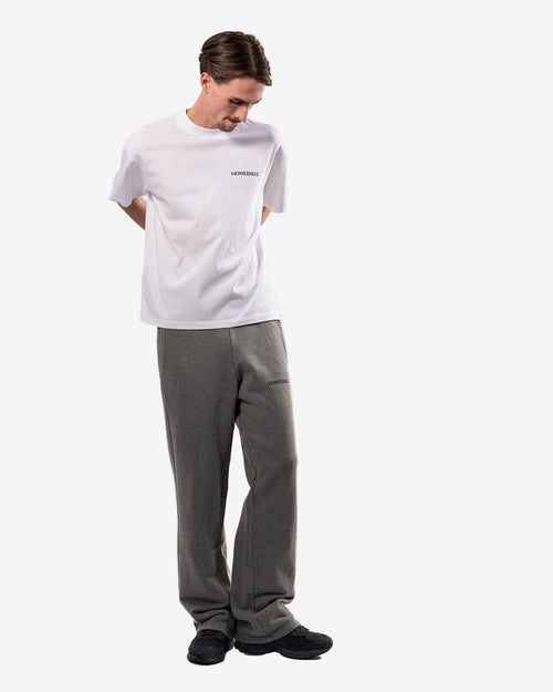 Person wearing a white t-shirt and gray pants on a white background