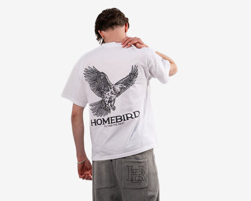 Person wearing a white t-shirt with an eagle design and 'Homebird' text, standing against a white background.